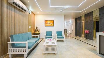 Una sala de estar moderna con un sofá, dos sillones, una mesa de centro y una estatua de Buda.