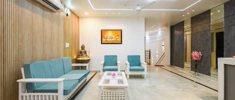 A modern living room with a sofa, two armchairs, a coffee table, and a Buddha statue.
