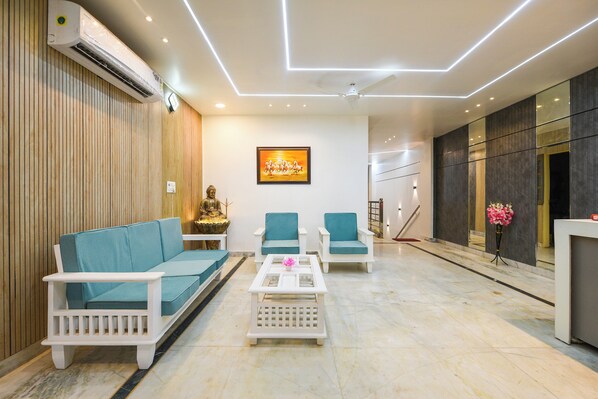 A modern living room with a sofa, two armchairs, a coffee table, and a Buddha statue.
