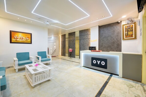 Zona de recepción de un hotel con un mostrador de recepción que dice 'OYO', asientos y un cuadro en la pared.