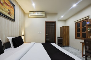 Una habitación de hotel con una cama, un armario, un escritorio y un cuadro en la pared.