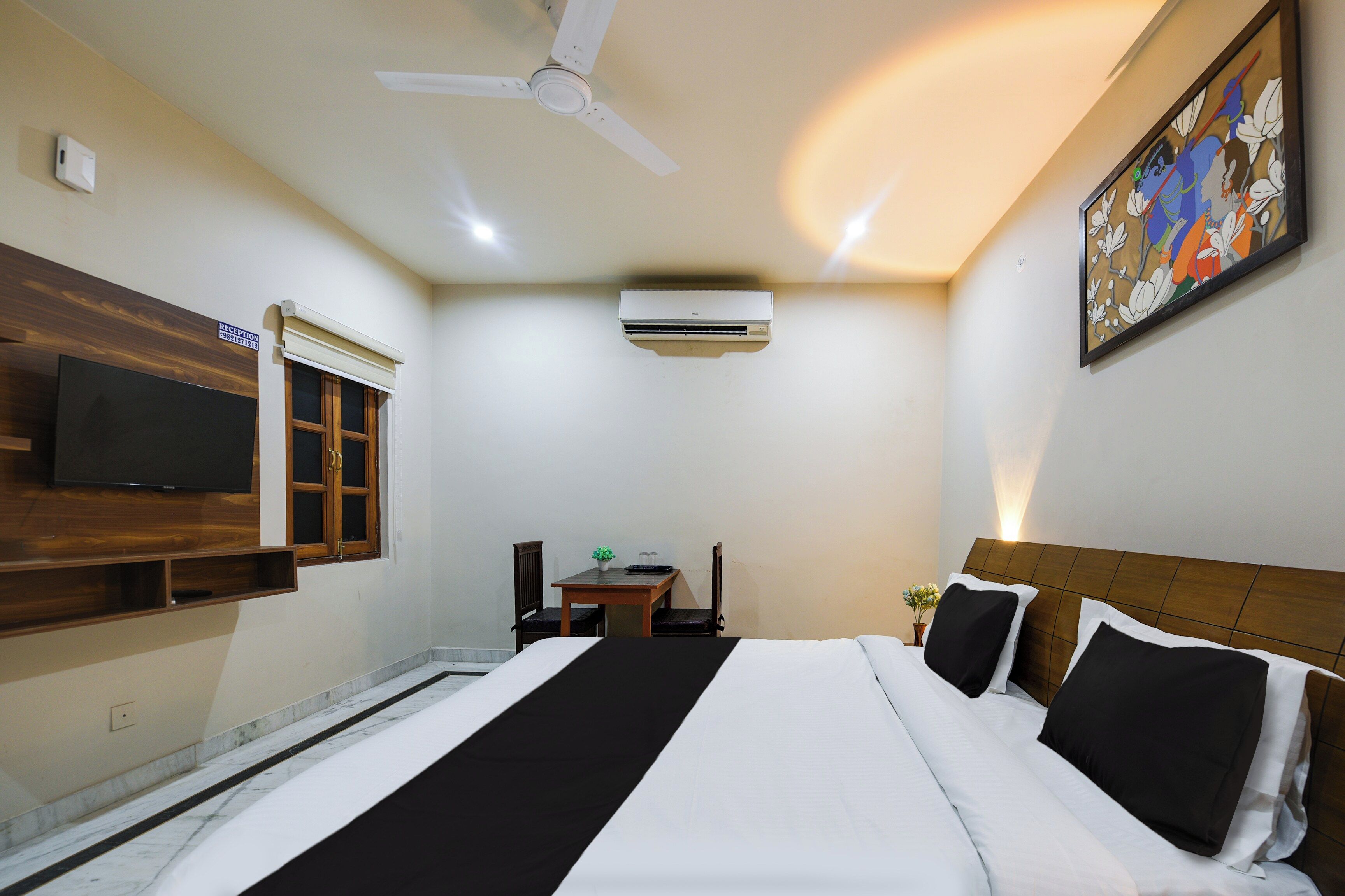 Une chambre d’hôtel avec un lit, un téléviseur à écran plat, un climatiseur et un tableau au mur.