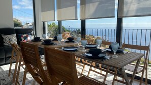 A dining area with a table set for four, overlooking a scenic view. - BLUE OCEAN VILLA with Private Heated Pool. Magnificent Seaview. AC, WIFI, Garden (Fajã da Ovelha, Calheta)