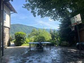 A courtyard with a ping pong table, a basketball hoop, and a stone-paved ground. - New Listing (Bodensdorf)