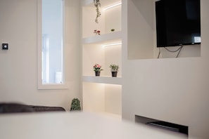 A modern room with a large window, built-in shelves with plants, a flat-screen TV mounted on the wall, and a bedside table. - Cosy 3 Bed | Sleeps 7 | Free Parking (Bristol City)