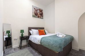 A bedroom with a bed, a nightstand, a lamp, a painting, and a mirror. - Cosy 3 Bed | Sleeps 7 | Free Parking (Bristol City)