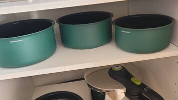 Une cuisine avec trois étagères, chacune contenant des casseroles et des poêles.