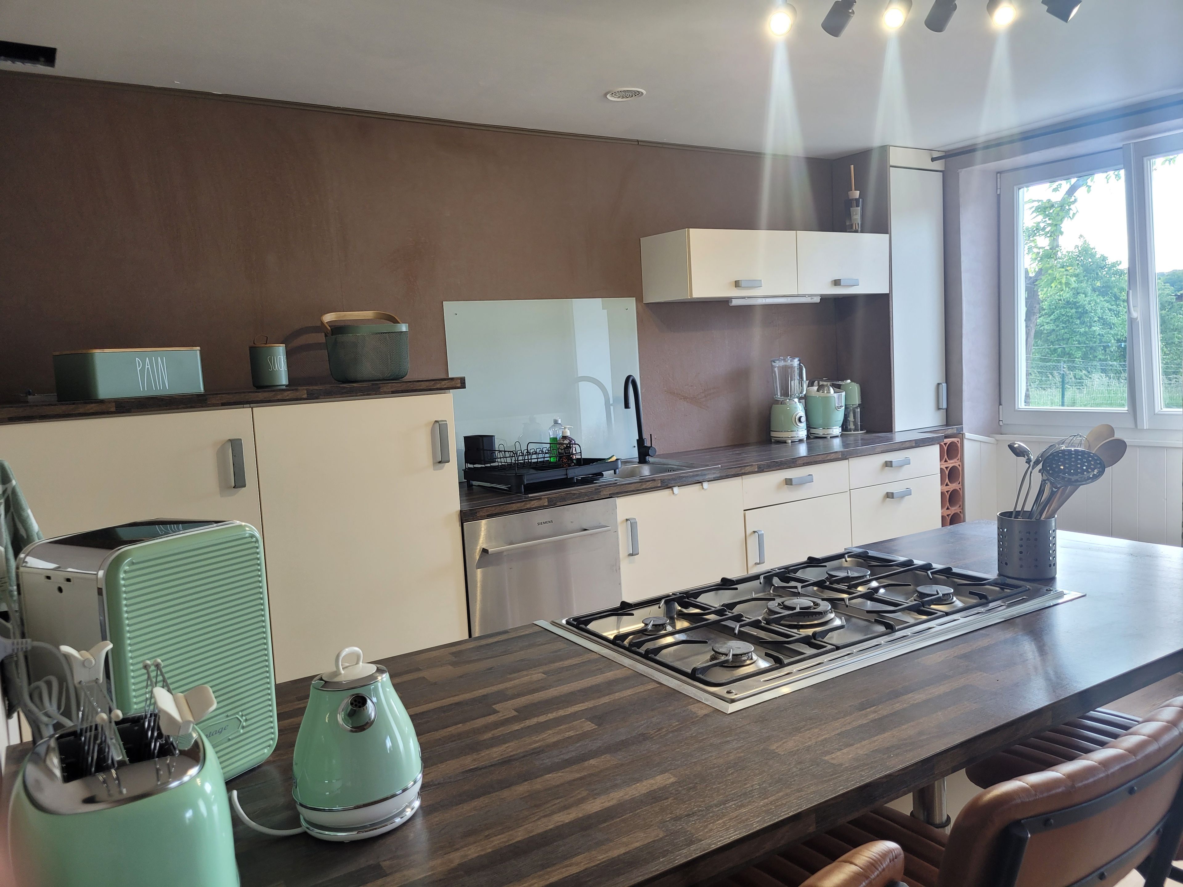 A modern kitchen with a gas stove, a dishwasher, and a countertop with various appliances.