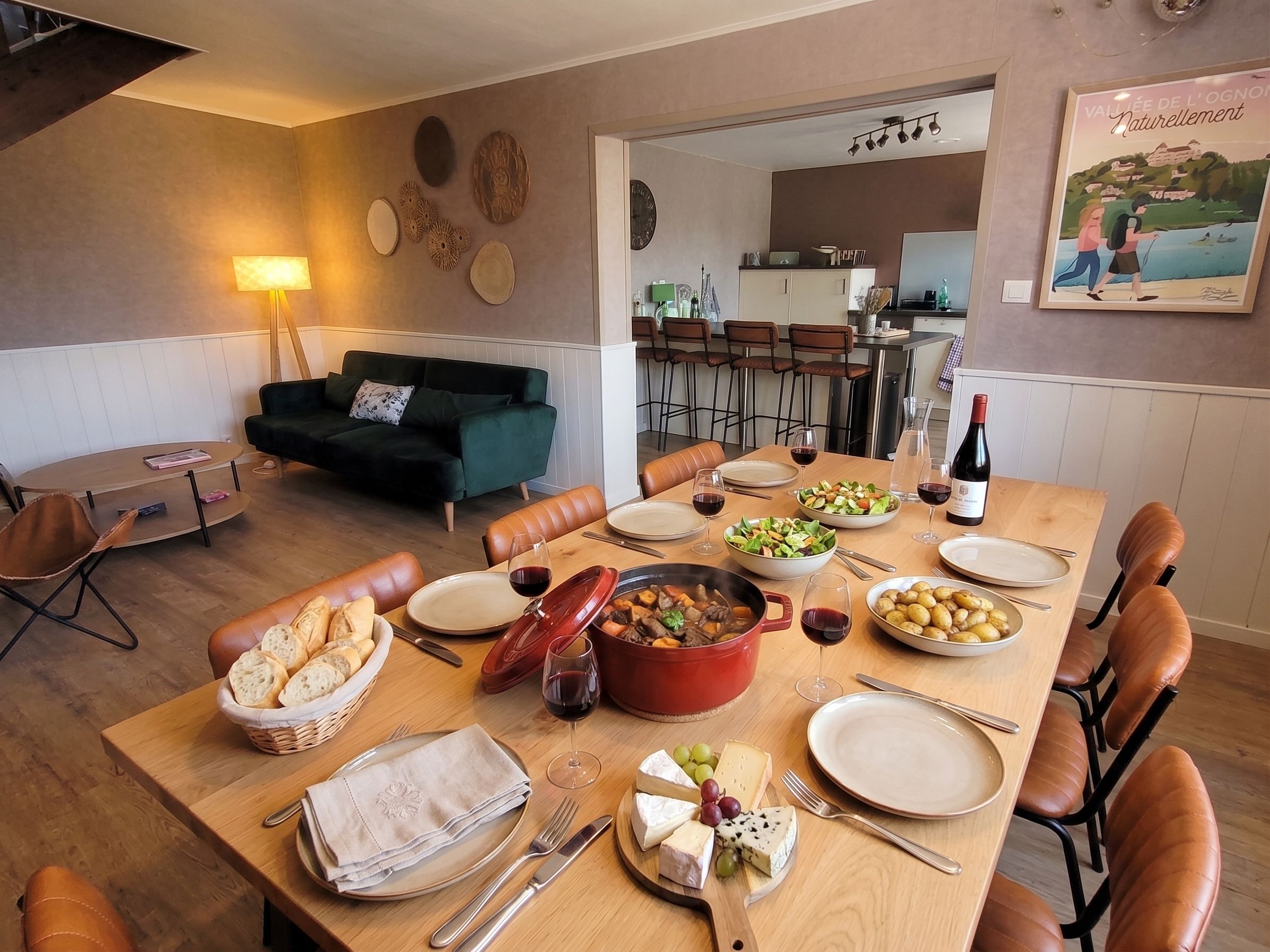 Un comedor con una mesa dispuesta para una comida, incluyendo pan, queso y un guiso.
