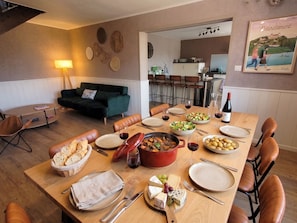 Un comedor con una mesa dispuesta para una comida, incluyendo pan, queso y un guiso.