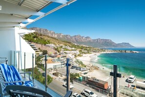 Ein Balkon mit Blick auf eine Küstenstadt, einen Strand und Berge in der Ferne.