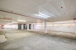 A parking garage with concrete floors, white walls, and red emergency exit signs. - Clifton 2 Bed Apartment Ocean Views Dunmore Noir (Cape Town)