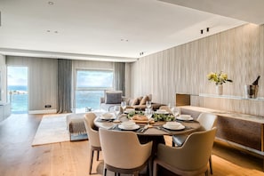 A modern dining area with a round table set for four, a sofa, and a view of the sea. - Clifton 2 Bed Apartment Ocean Views Dunmore Noir (Cape Town)
