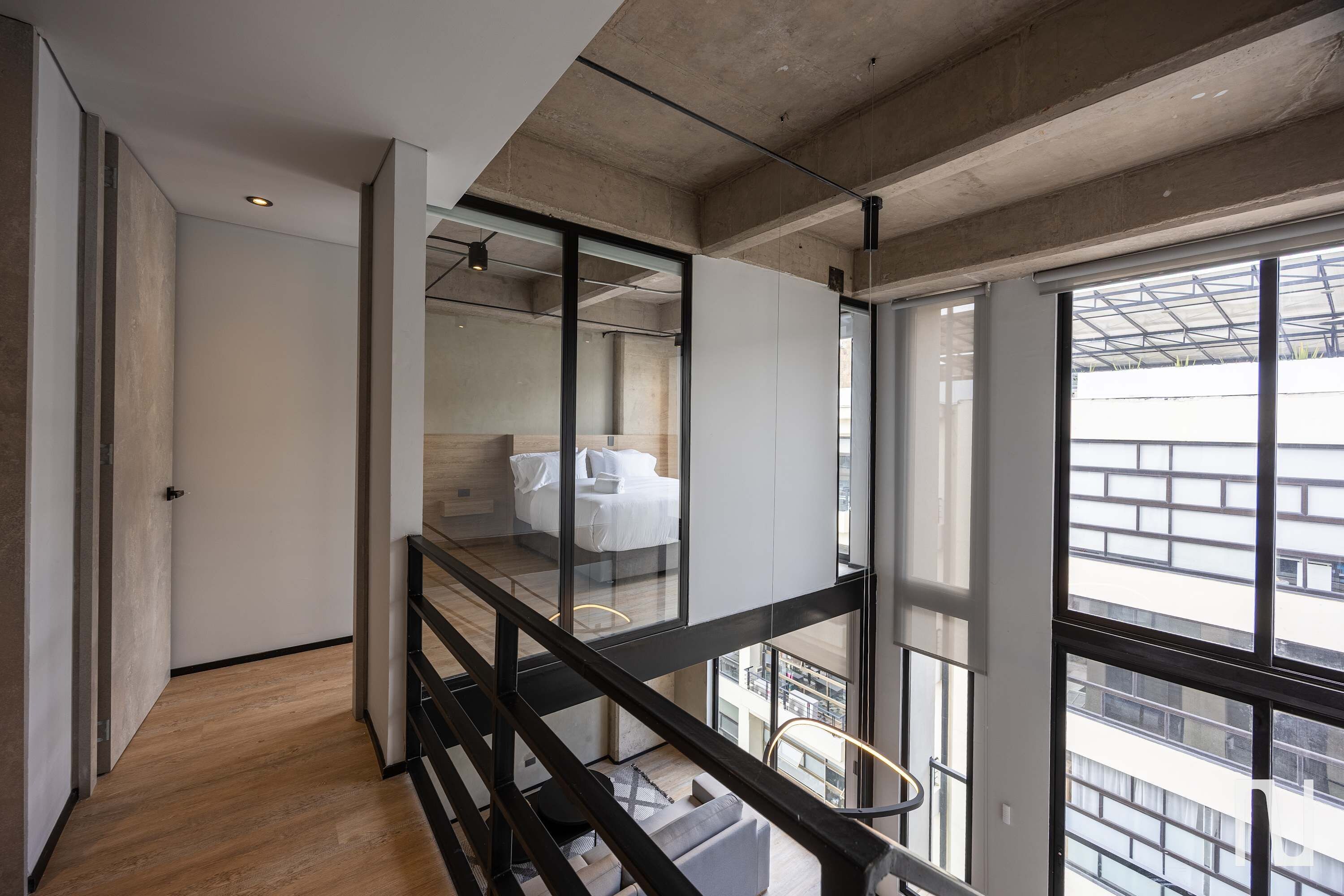 A modern interior with a wooden floor, a glass partition, and a view of the city through large windows.