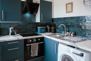 A compact kitchen with a washing machine, a coffee maker, and a sink. - Sea-view Herne Bay Apartment Parking Sleeps 5 (Herne Bay)