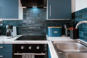A modern kitchen with a Bosch coffee maker, a blue container, and a sink. - Sea-view Herne Bay Apartment Parking Sleeps 5 (Herne Bay)
