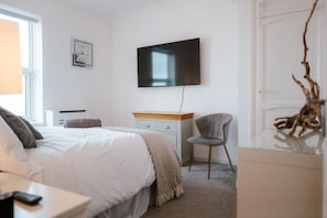 A bedroom with a bed, a desk, a chair, a television, and a clock on the wall. - Sea-view Herne Bay Apartment Parking Sleeps 5 (Herne Bay)