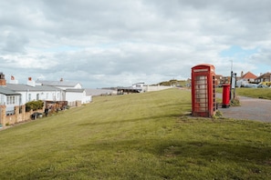 A grassy hill with a red telephone booth and a white building in the background. - Sea-view Herne Bay Apartment Parking Sleeps 5 (Herne Bay)