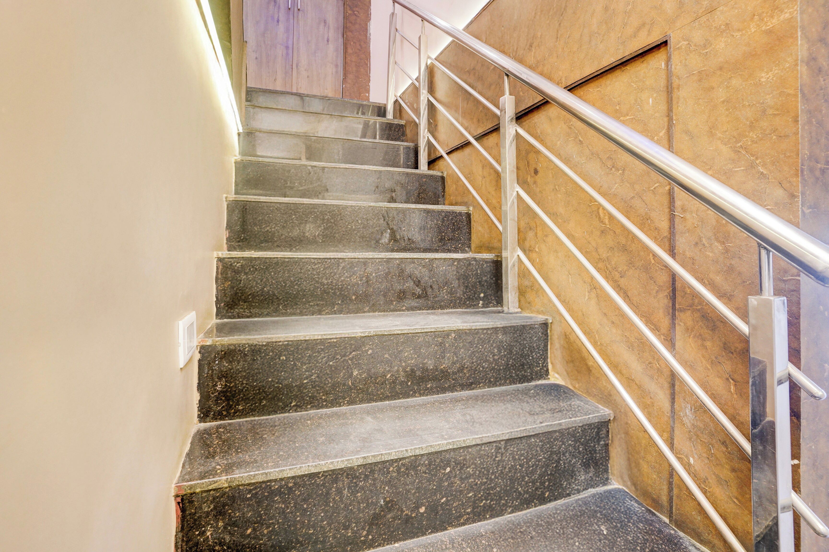 Una escalera con barandilla de metal y una pared con panel de madera.