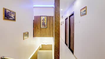 Un pasillo de hotel con paneles de madera, una columna de mármol y obras de arte enmarcadas en las paredes.