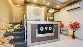 Una mesa de recepción con un cartel que dice 'OYO' y un reloj encima.