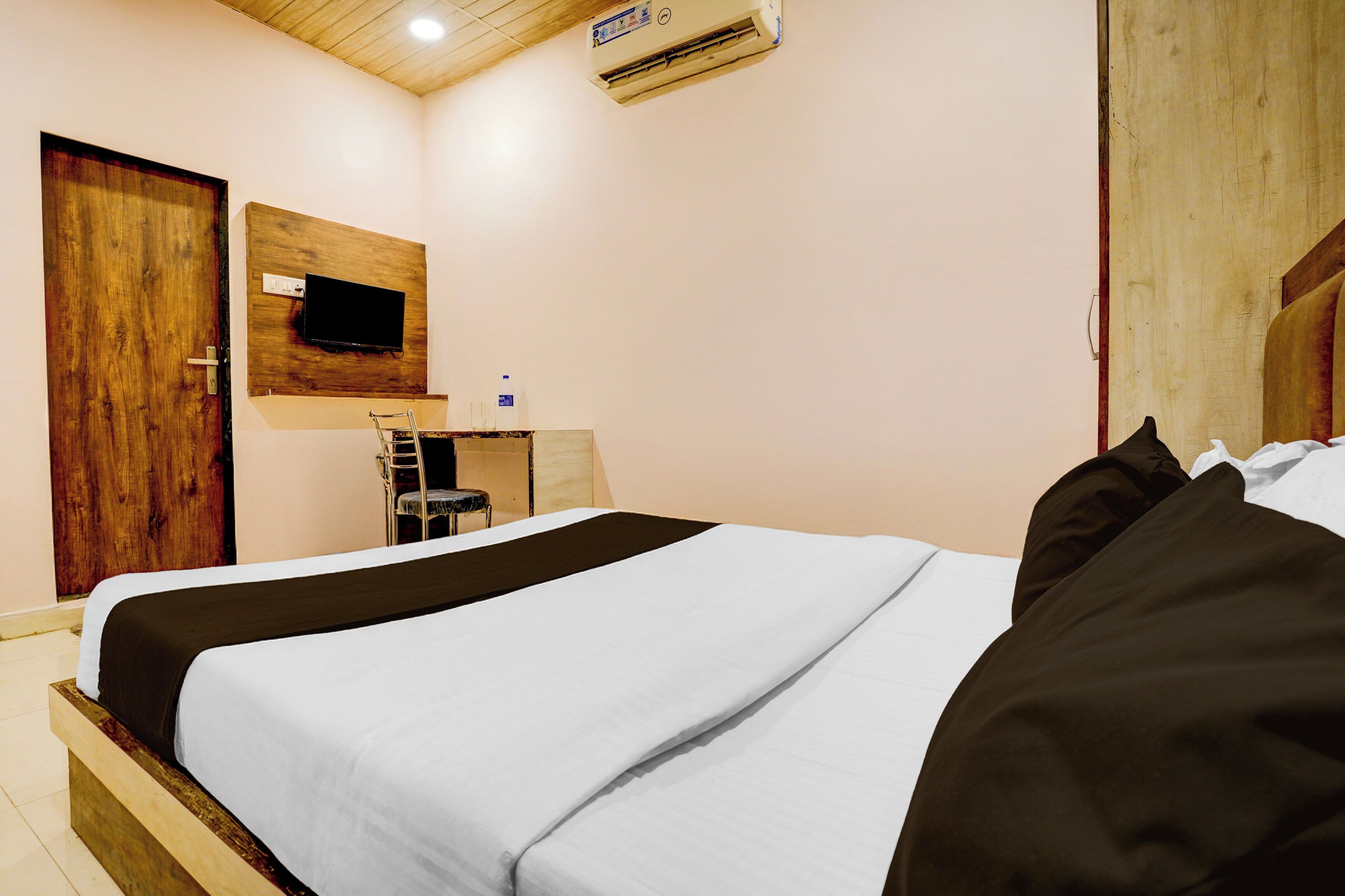 Un dormitorio con una cama, un televisor en la pared y un equipo de aire acondicionado.