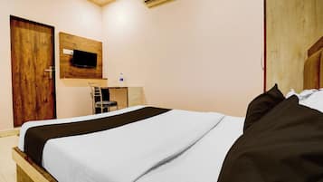 Un dormitorio con una cama, un televisor en la pared y un equipo de aire acondicionado.