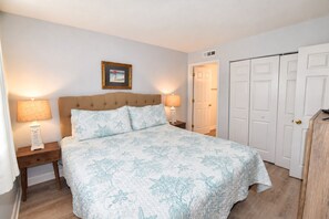 A bedroom with a bed, two bedside tables with lamps, a framed picture on the wall, and a wardrobe. - Oceanfront 2bed/2bath-Water's Edge Resort-211 Indoor/Outdoor Pool & Hot Tub (Murrells Inlet)