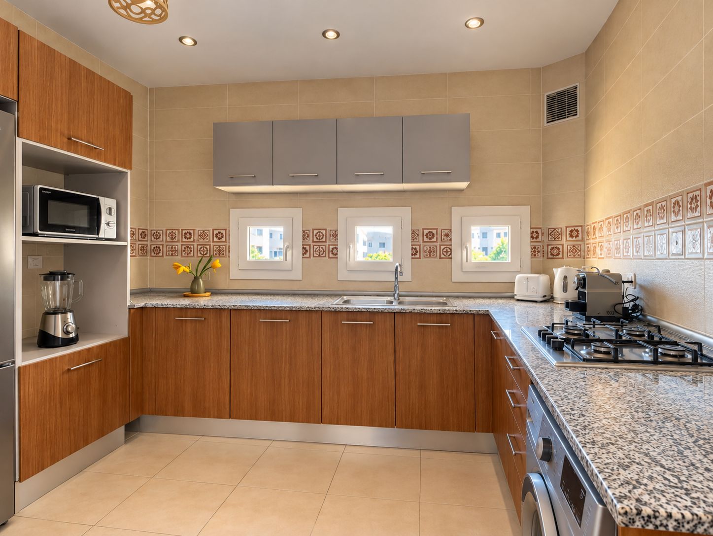 A modern kitchen with wooden cabinets, a built-in microwave, a gas stove, and a window with a view of buildings.
