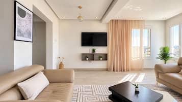 A modern living room with a sofa, a coffee table, a TV, and a window with curtains.