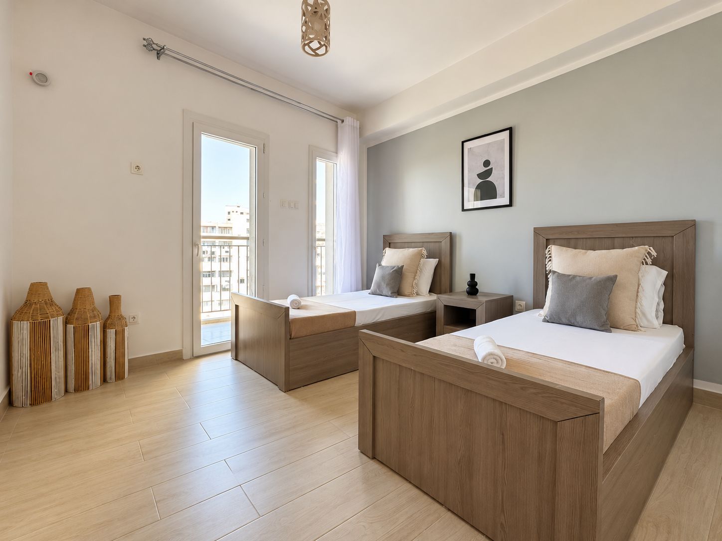 A hotel room with two beds, a balcony, and a view of the city.