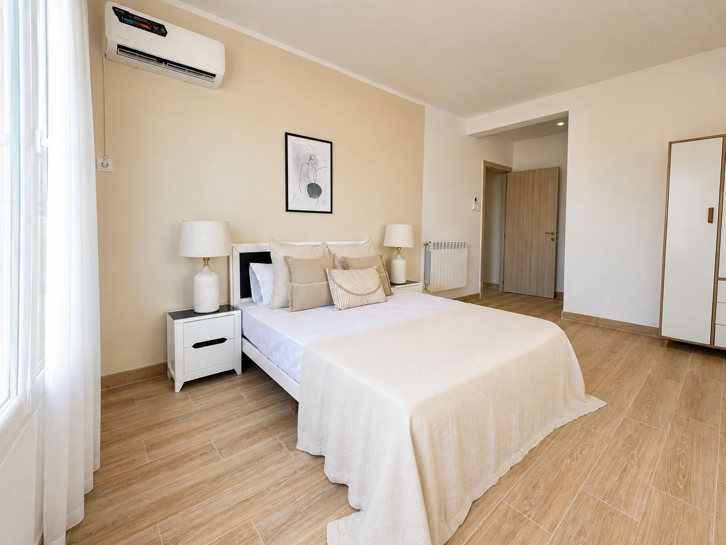 A bedroom with a bed, bedside tables, a radiator, and an air conditioning unit.