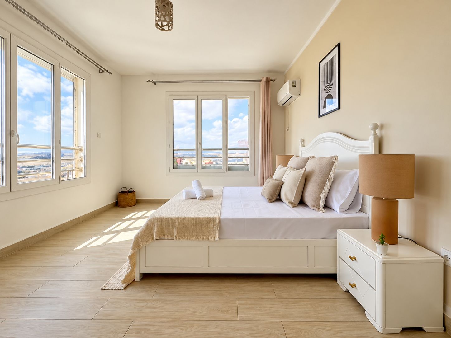 A bedroom with a large bed, bedside tables, a nightstand, a window with a view, and a ceiling light fixture.