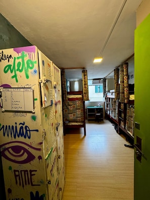 Un pasillo con taquillas, un panel de recepción y una cama con cortinas estampadas.