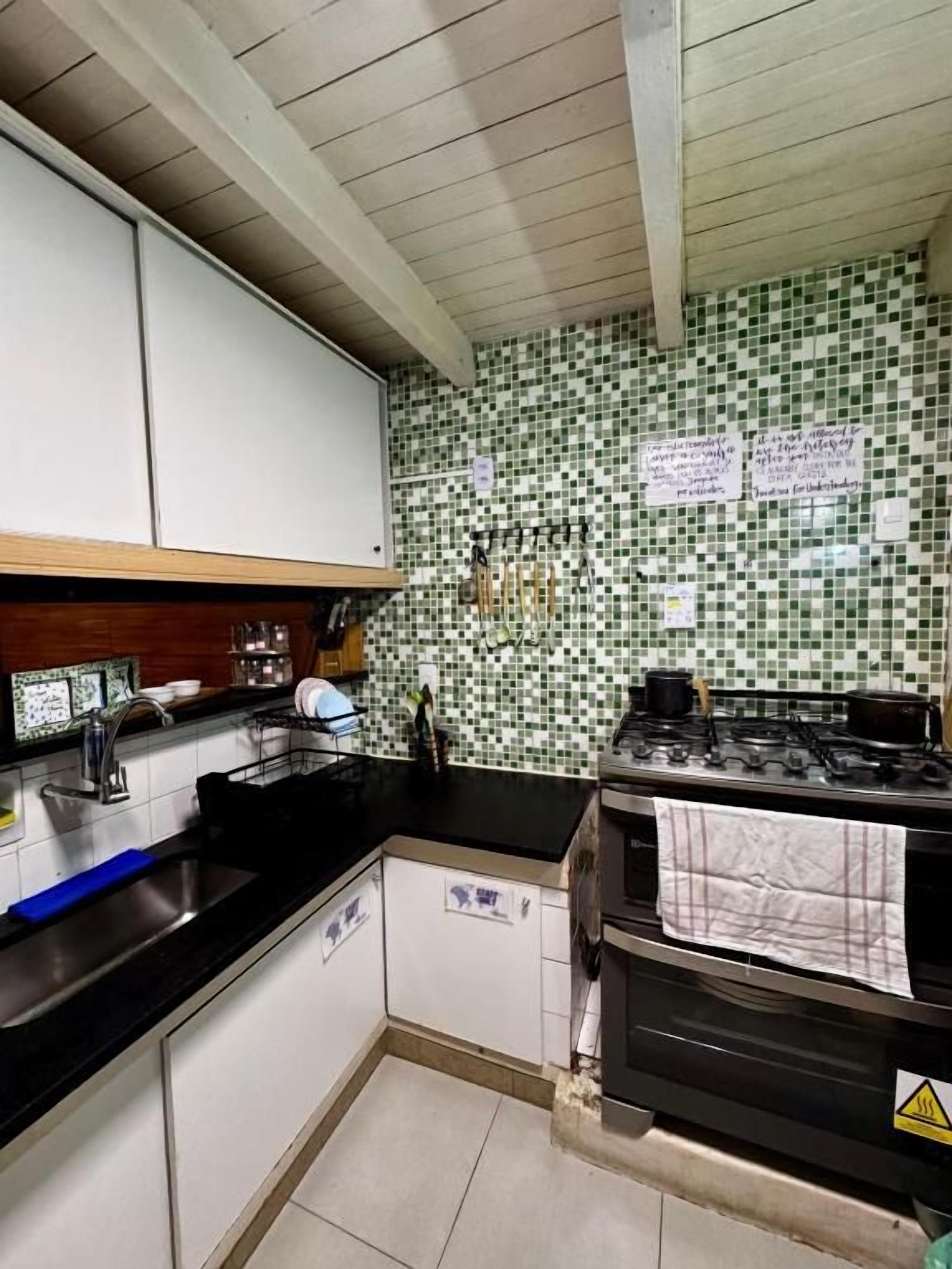 Una cocina con armarios blancos, encimera negra, salpicadero de azulejos y estufa.