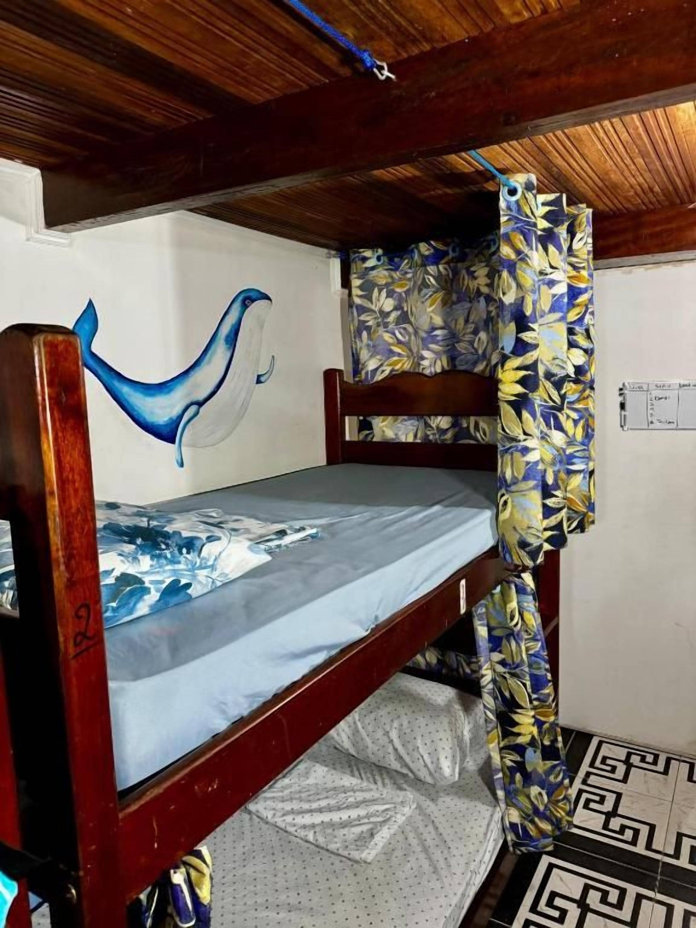 A bunk bed with a blue whale mural on the wall, patterned curtains, and a geometric floor design.