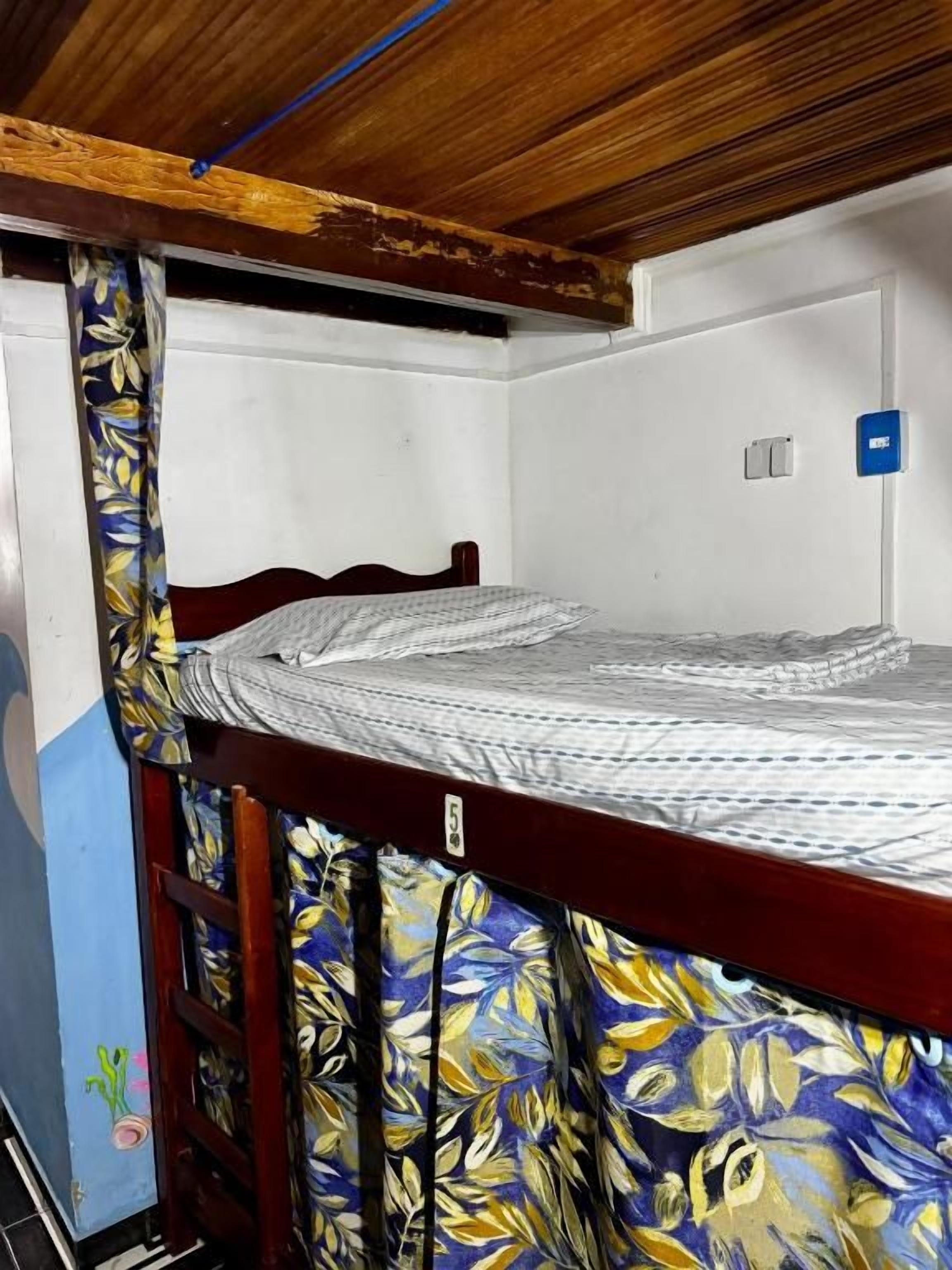 A bunk bed with a wooden headboard and a patterned curtain.