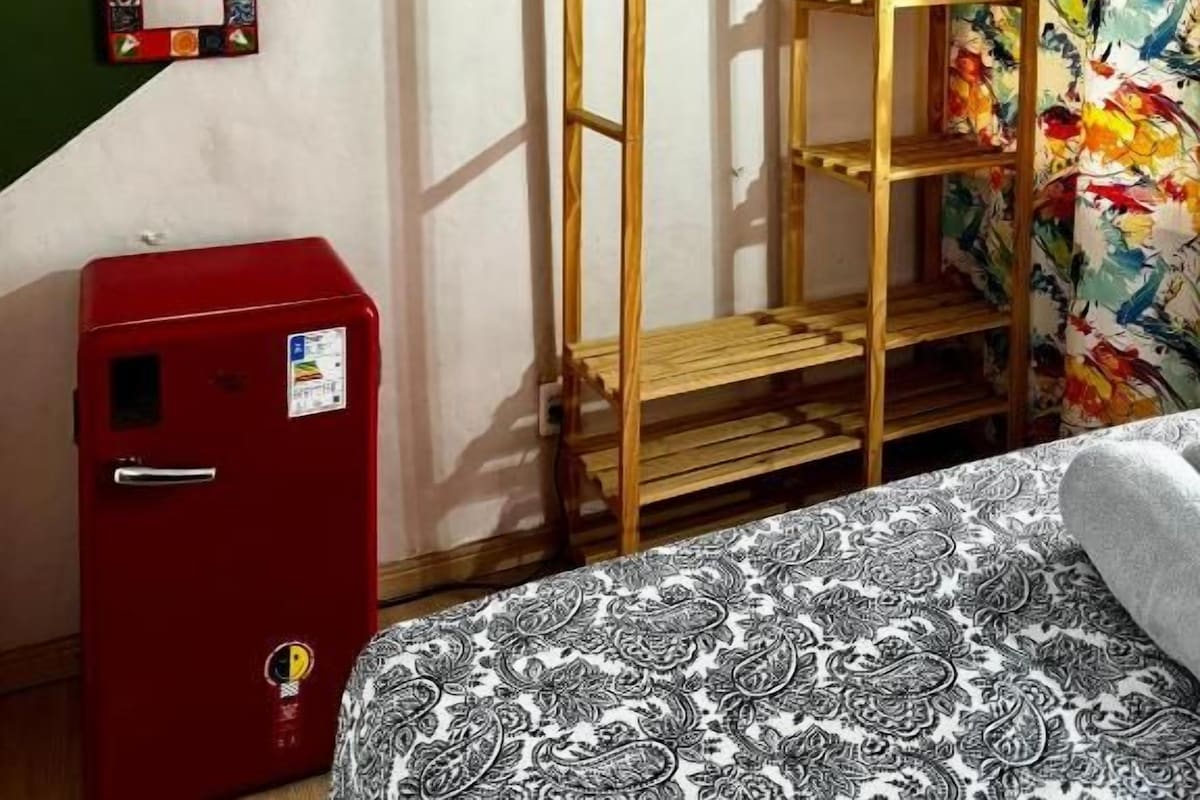 Ein Zimmer mit einem Etagenbett, einem roten Koffer, einer Holzleiter und einem farbenfrohen Wandgemälde.