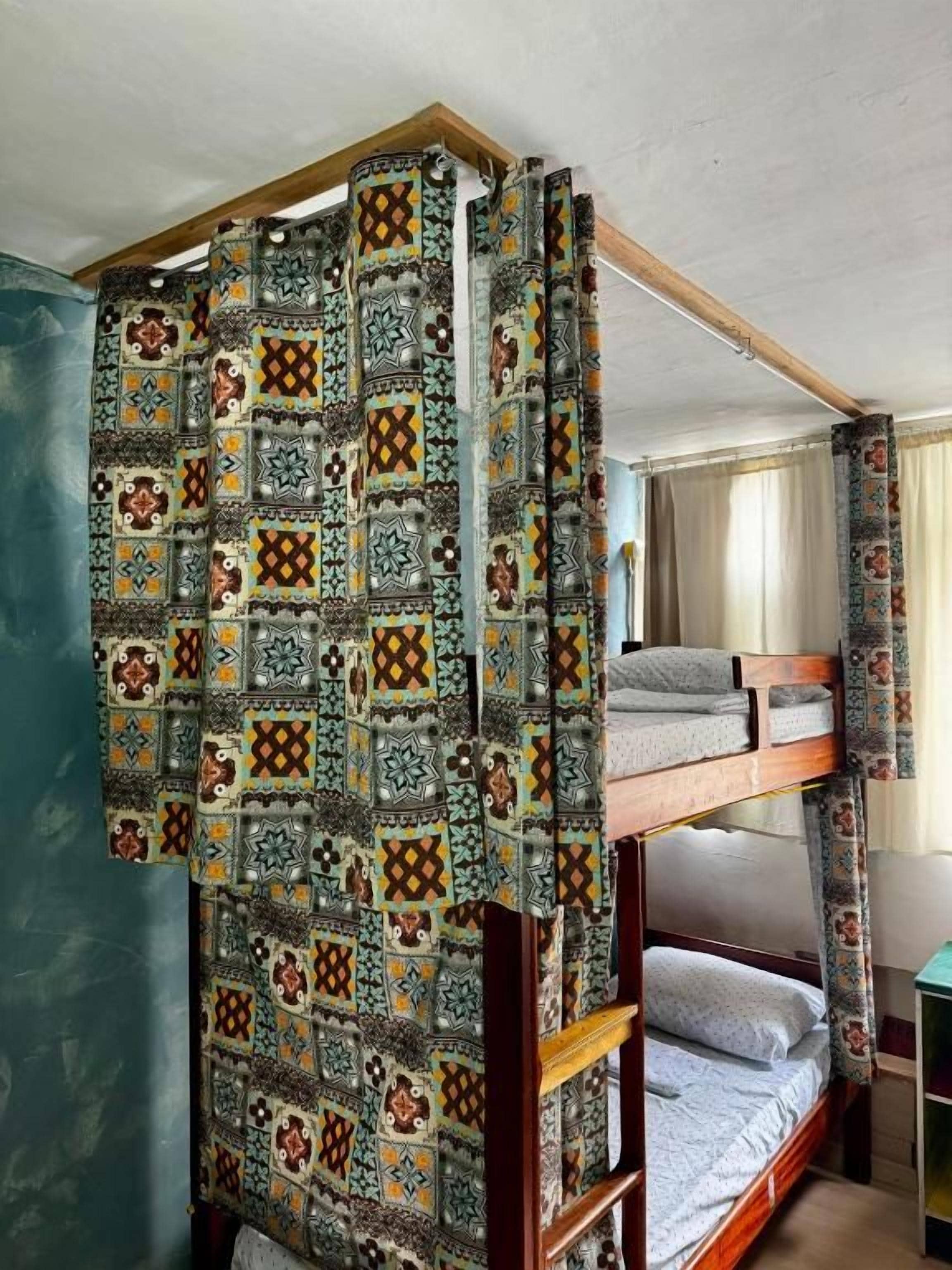 A room with a bunk bed and a patterned curtain.