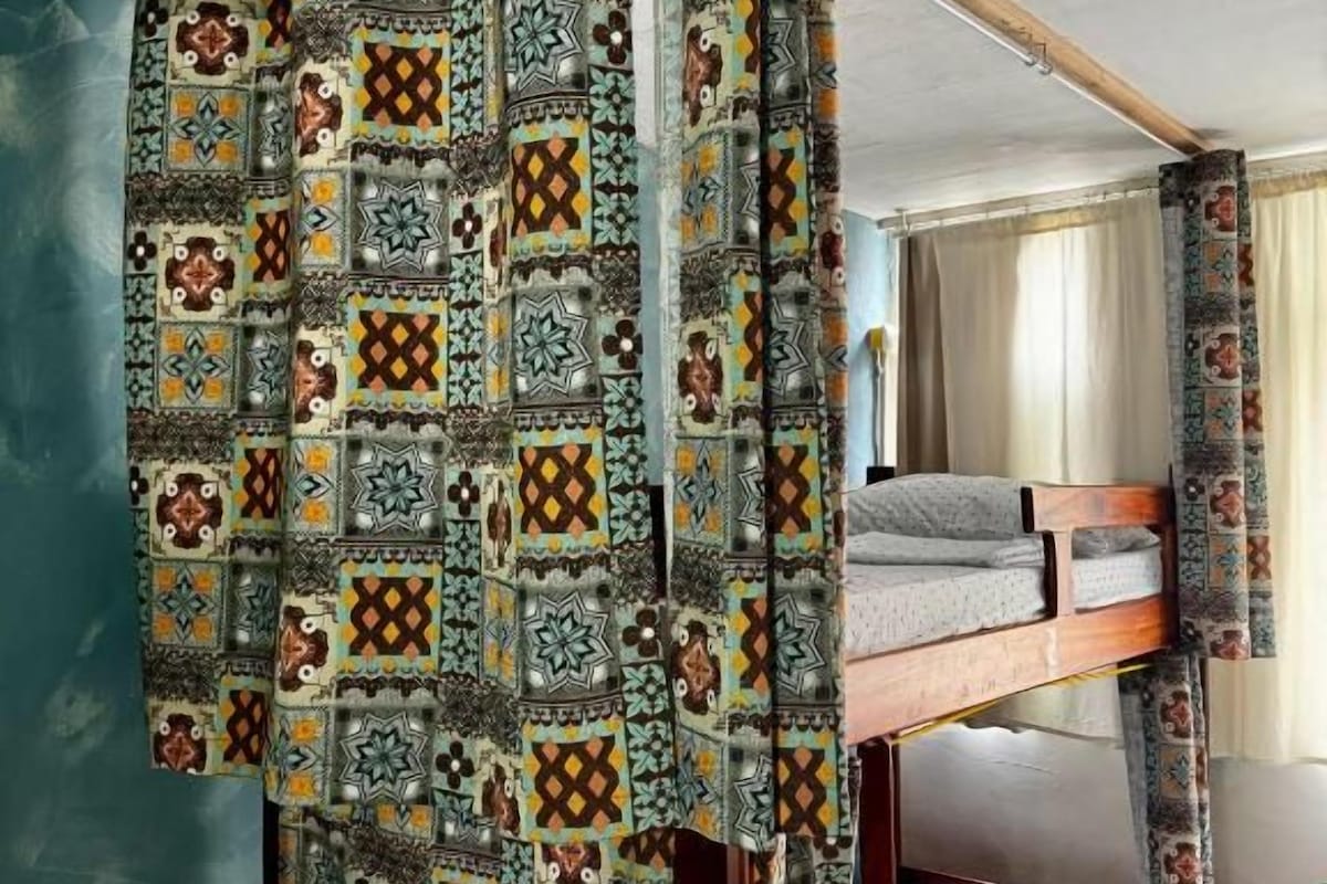 Ein Zimmer mit Etagenbett und einem gemusterten Vorhang.