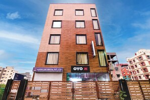 A multi-story building with a sign for 'ALEXIS CAR RENTAL PVT. LTD.' and 'OYO Hotel Sun Shine' on the ground floor. - Hotel O Sunshine Near Netaji Subhash (Kolkata)