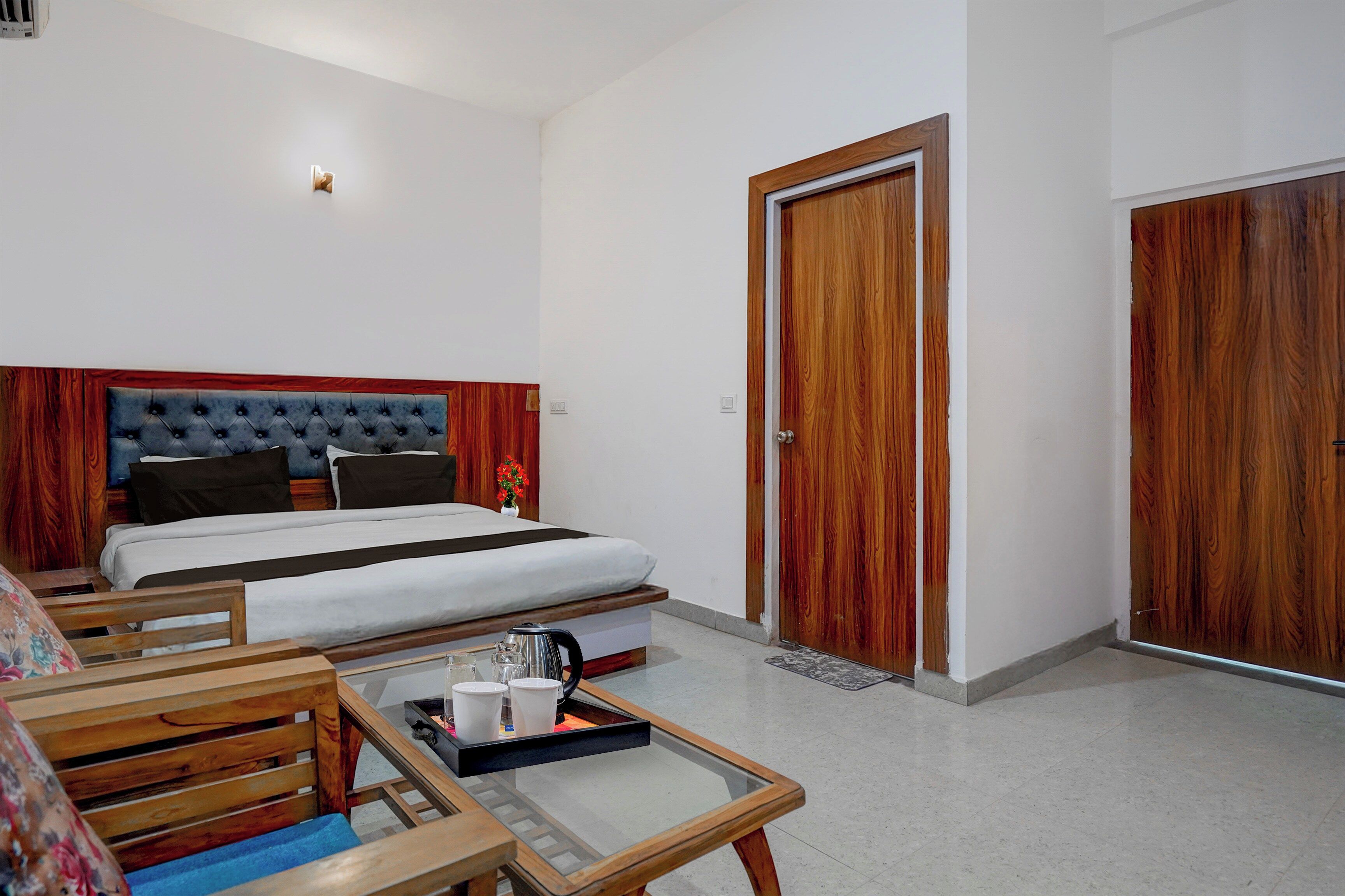 Ein Hotelzimmer mit einem Bett, einem Holz-Kopfteil, einem Couchtisch mit Tassen und einer Tür.