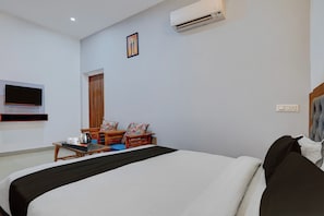 A hotel room with a bed, a TV mounted on the wall, a wooden door, and a small table with a kettle and cups. - Super Hotel O Greater Noida West Link (Greater Noida)