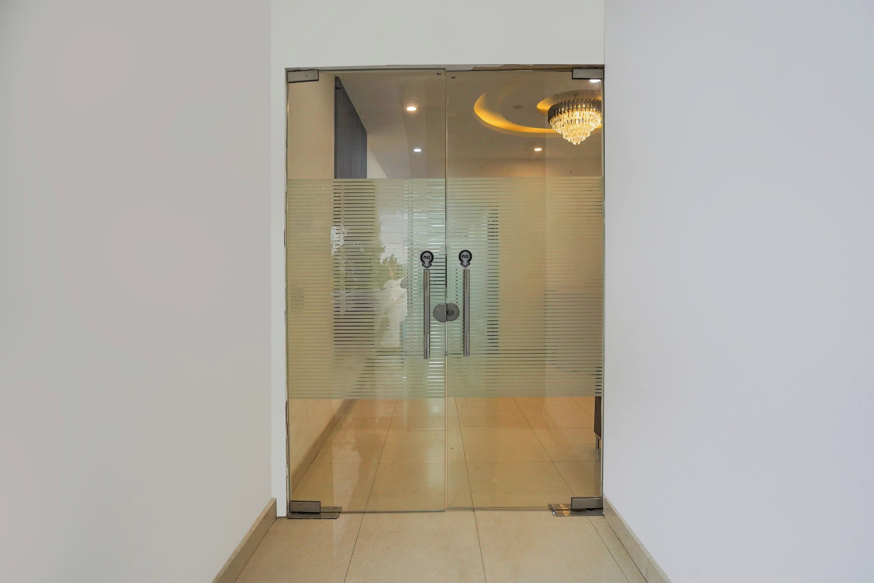 Un interior moderno con una puerta de vidrio esmerilado, un tirador y una lámpara de araña.