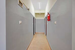 A corridor with grey walls, a fire extinguisher, and a ceiling light fixture.