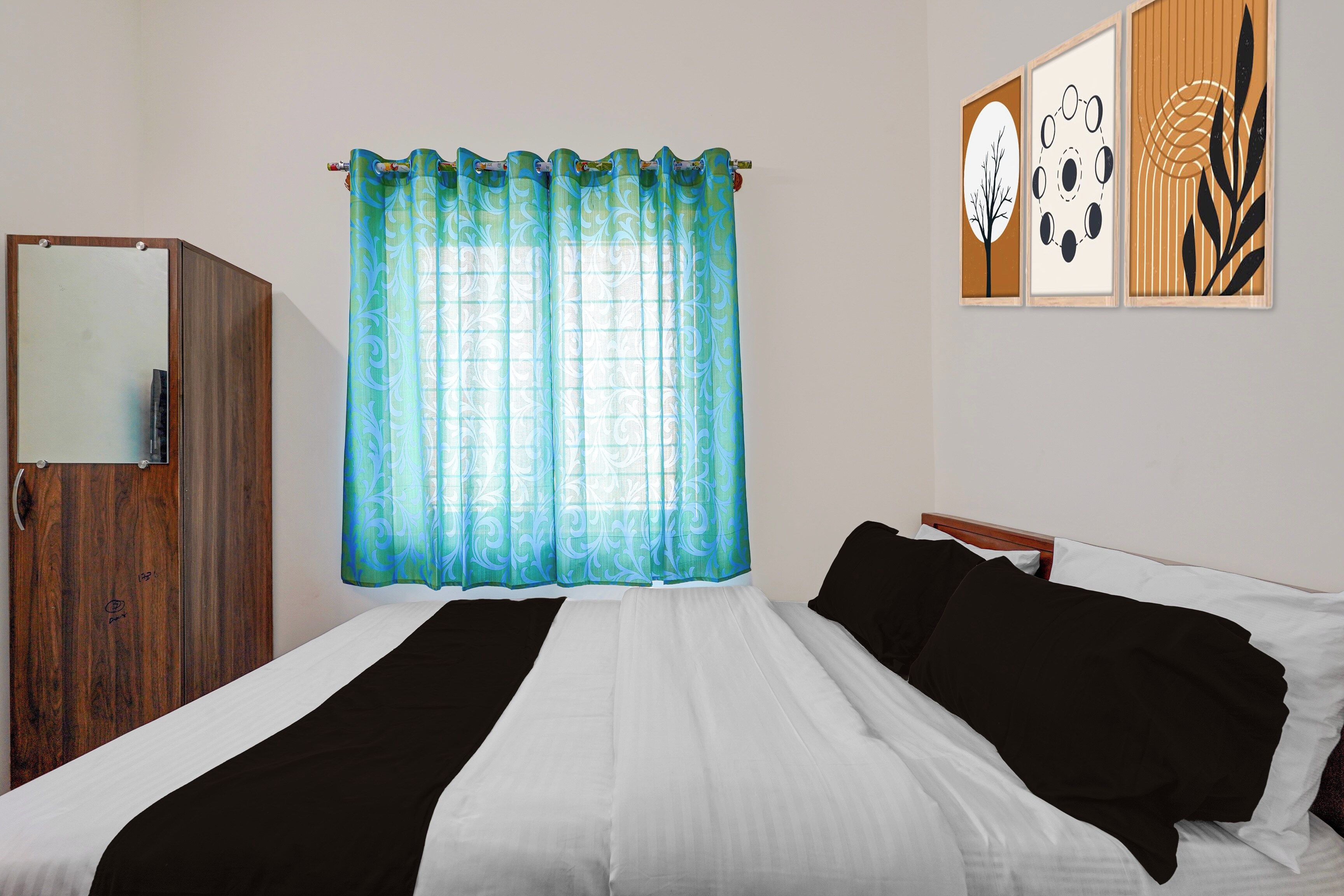 Une chambre à coucher comprenant un lit, une armoire, une fenêtre avec des rideaux et des œuvres d’art murales.