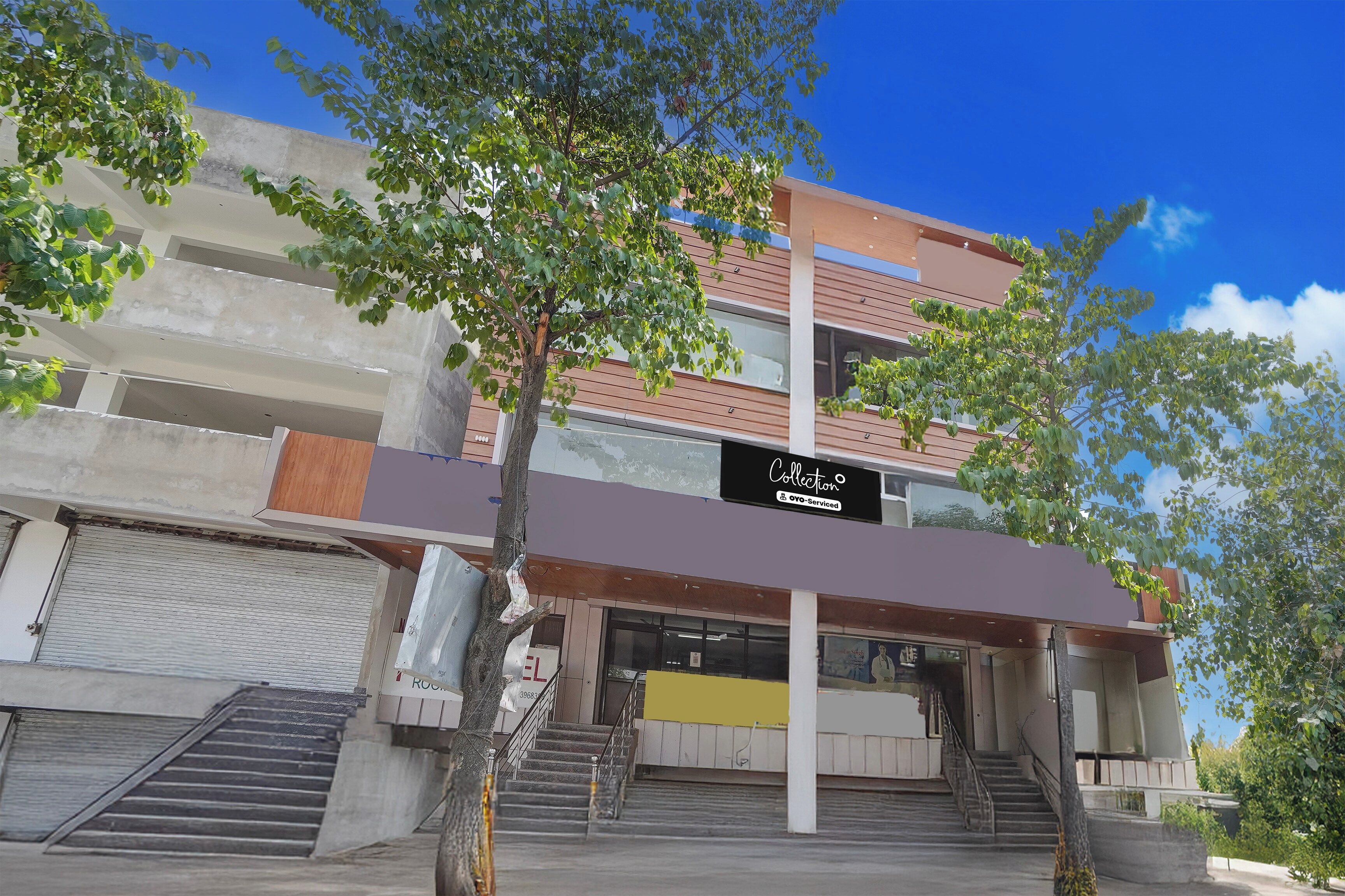 A multi-story building with a modern architectural design, featuring a prominent staircase leading to the entrance, and a sign indicating a collection service.