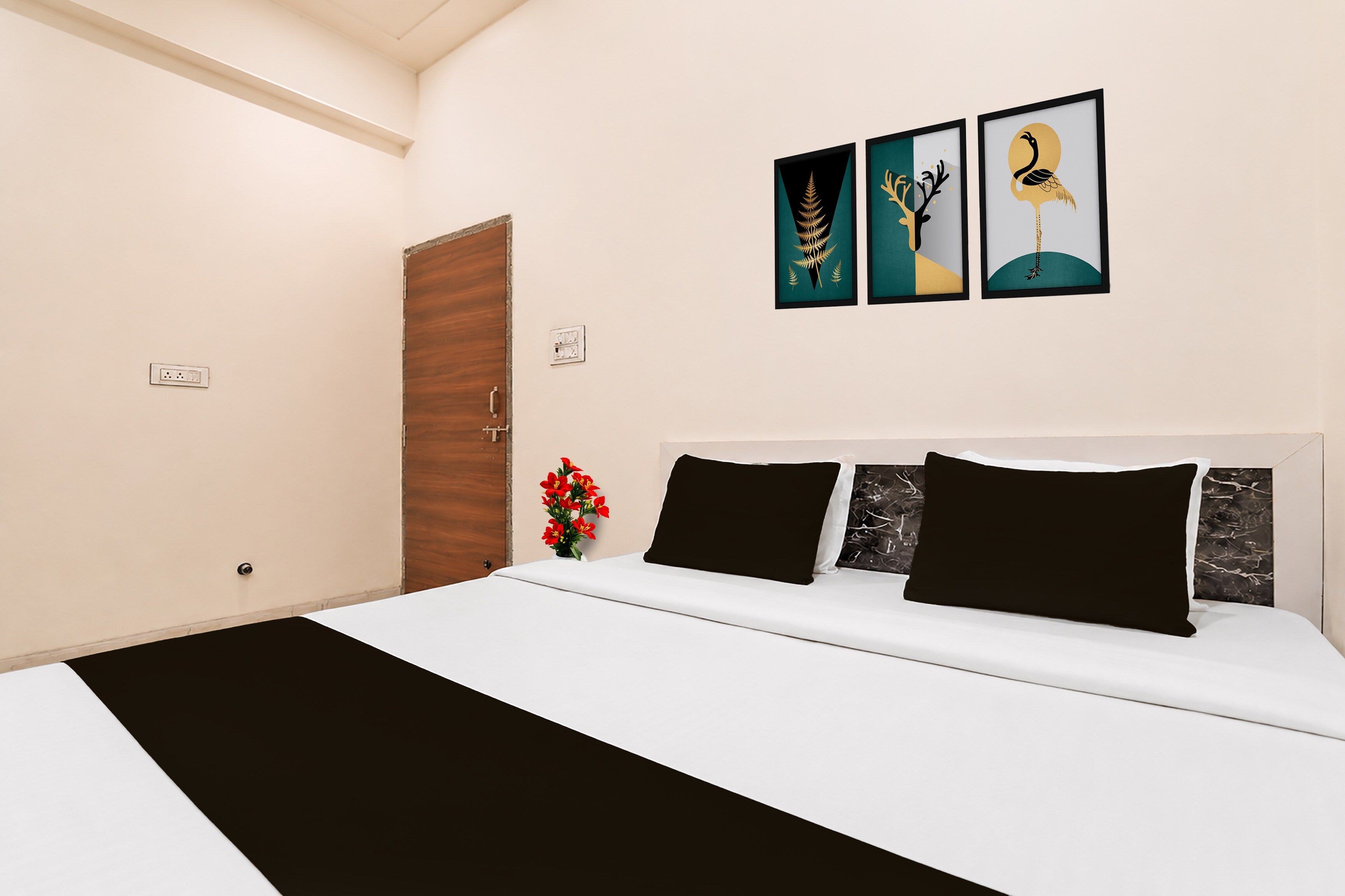 Une chambre à coucher avec un lit, une porte en bois et trois œuvres d’art encadrées accrochées au mur.