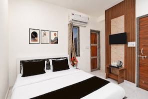 A hotel room with a bed, a TV, a window with curtains, and artwork on the wall. - Hotel O Khatu Shyam Temple (Danta Ramgarh)