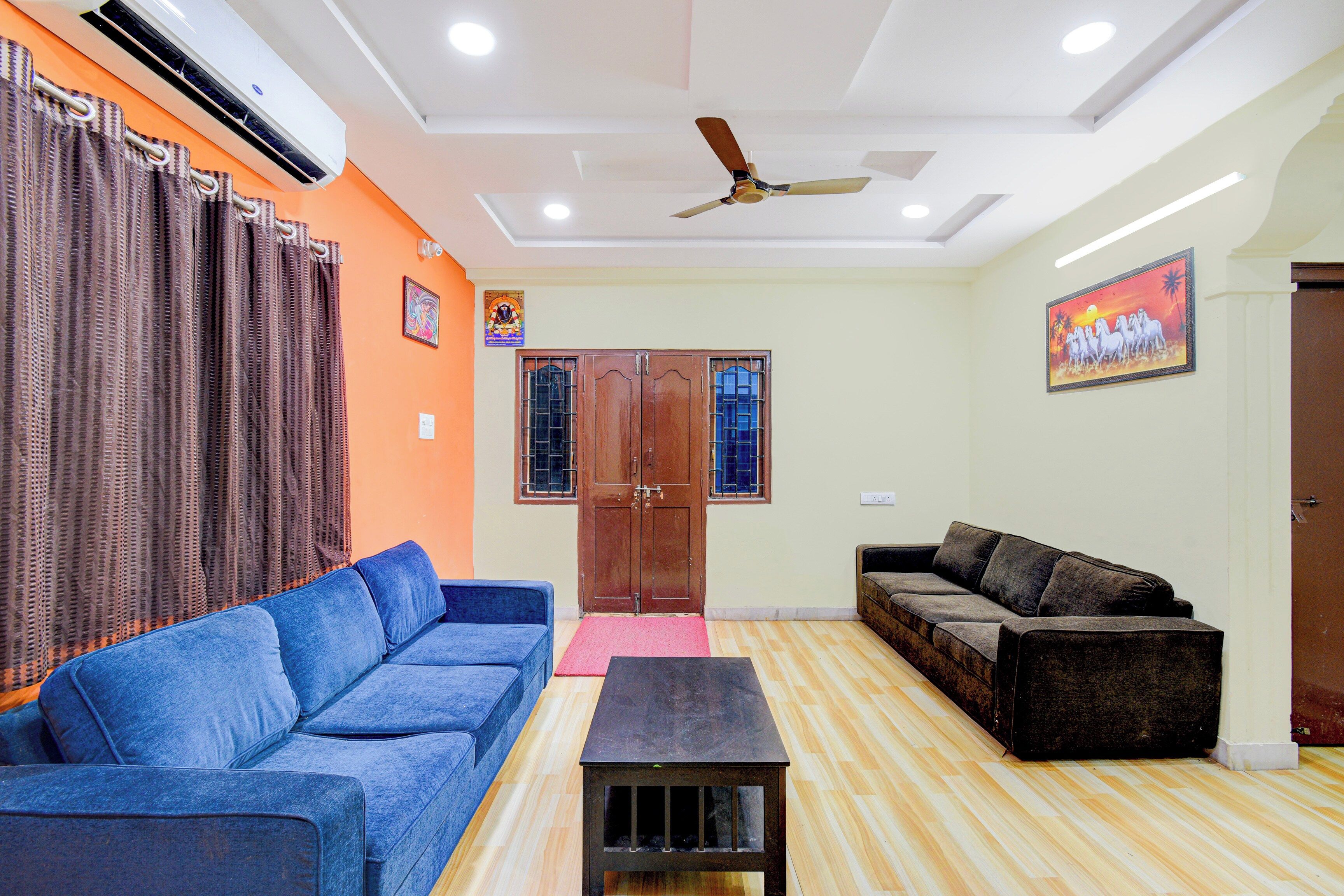 A living room with a blue sofa, a brown sofa, a wooden coffee table, and a ceiling fan.